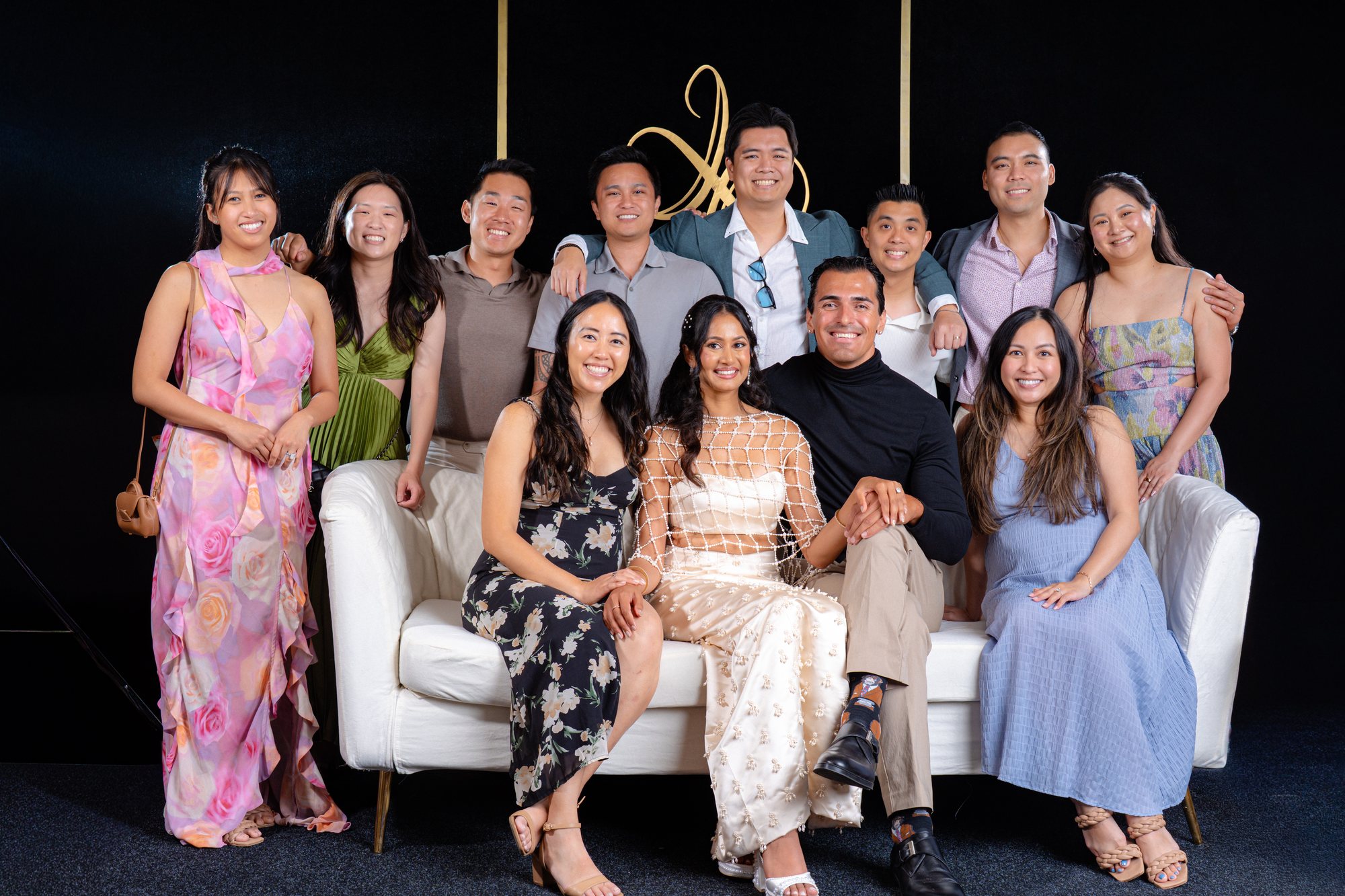 Twelve-person wedding party smiling around the white sofa on the Portrait Lounge set