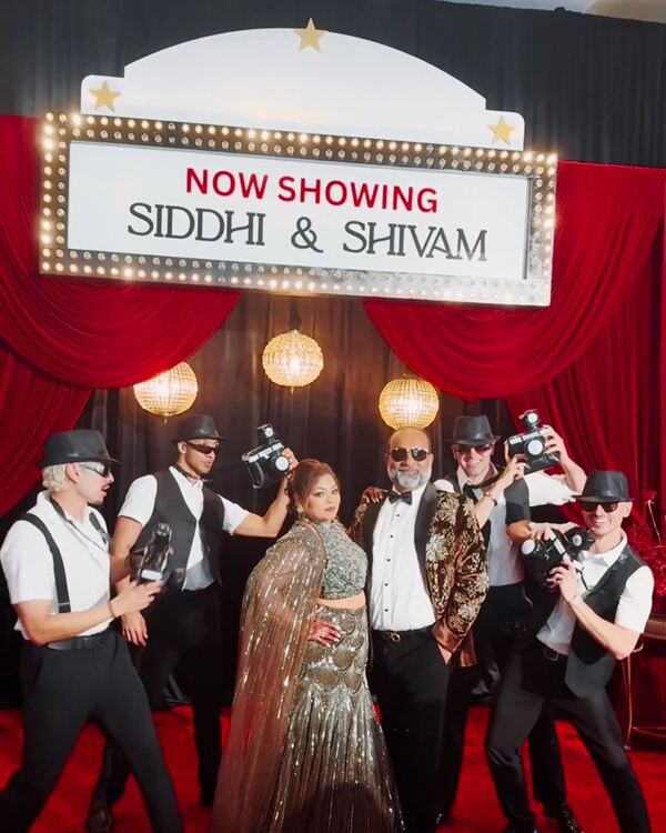 Custom movie-premiere photo booth set with a Now Showing marquee, red curtains and a red carpet at a wedding