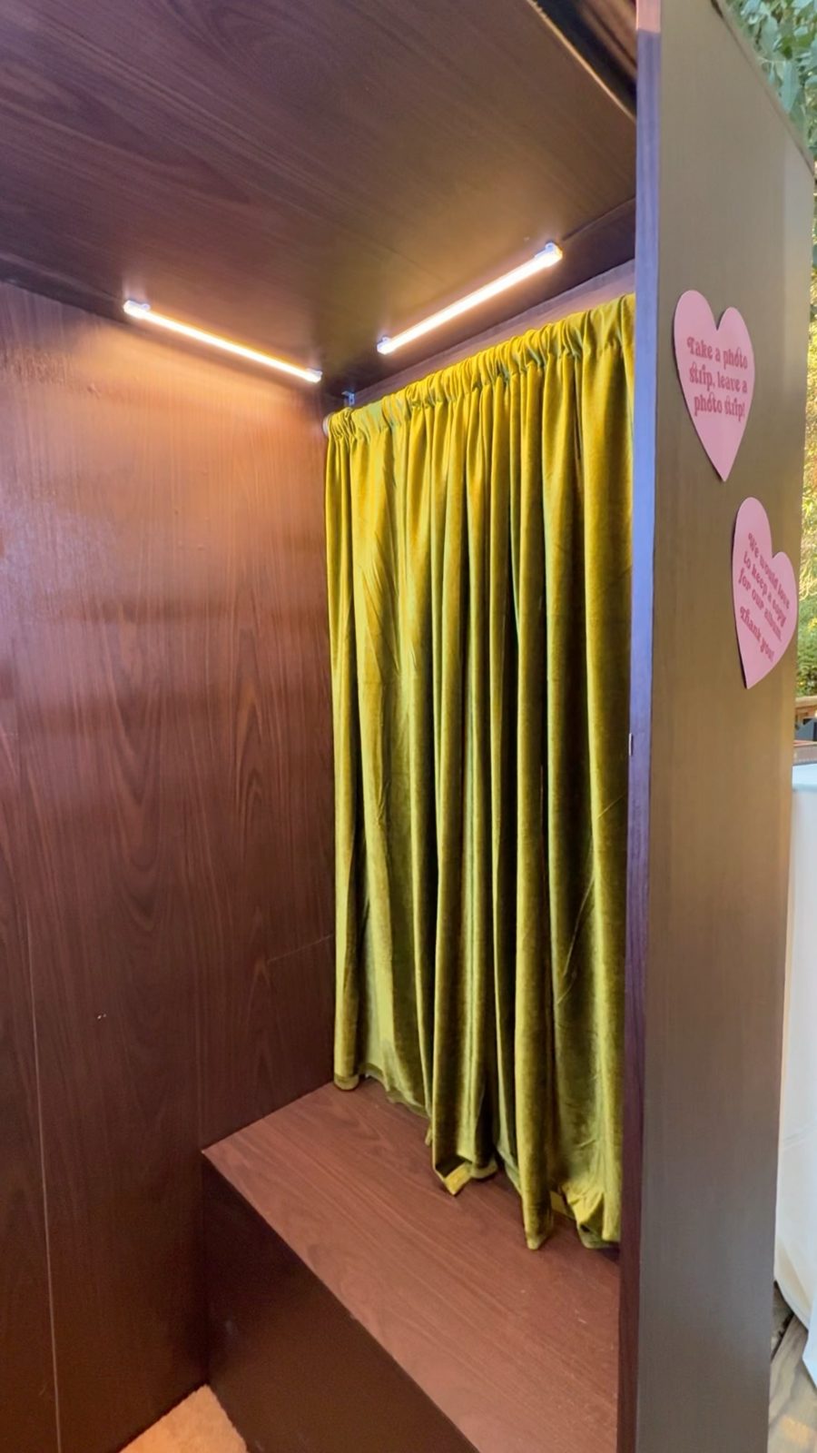 Inside the Vintage Booth: wood-grain walls, a bench, LED light bars and an olive green velvet backdrop