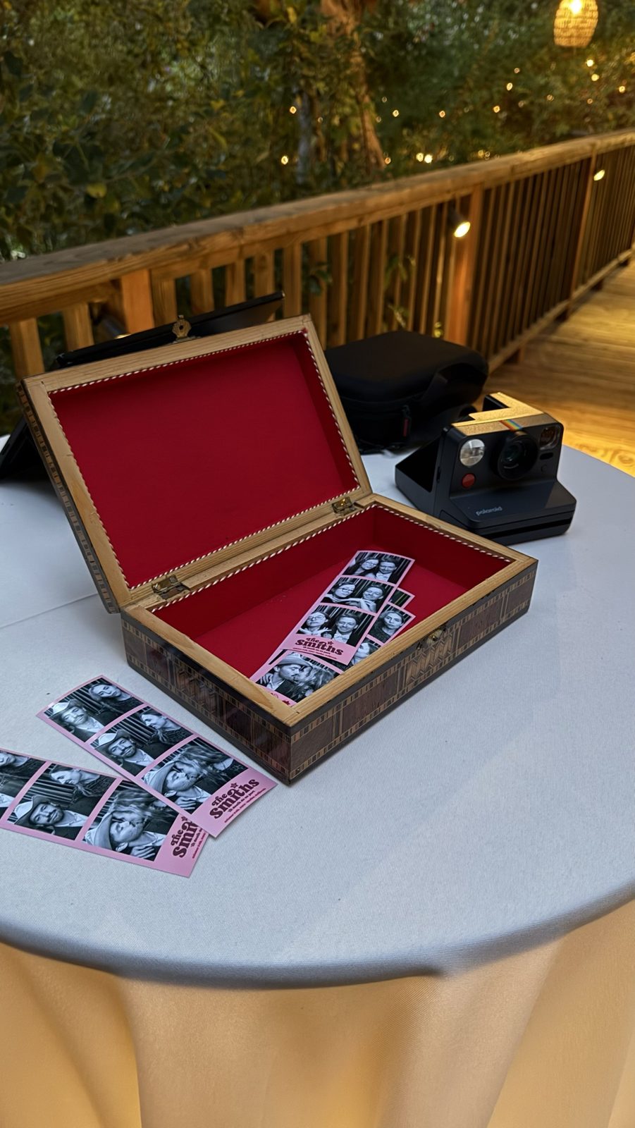 Wedding photo strips collected in a red-velvet-lined keepsake box on a cocktail table