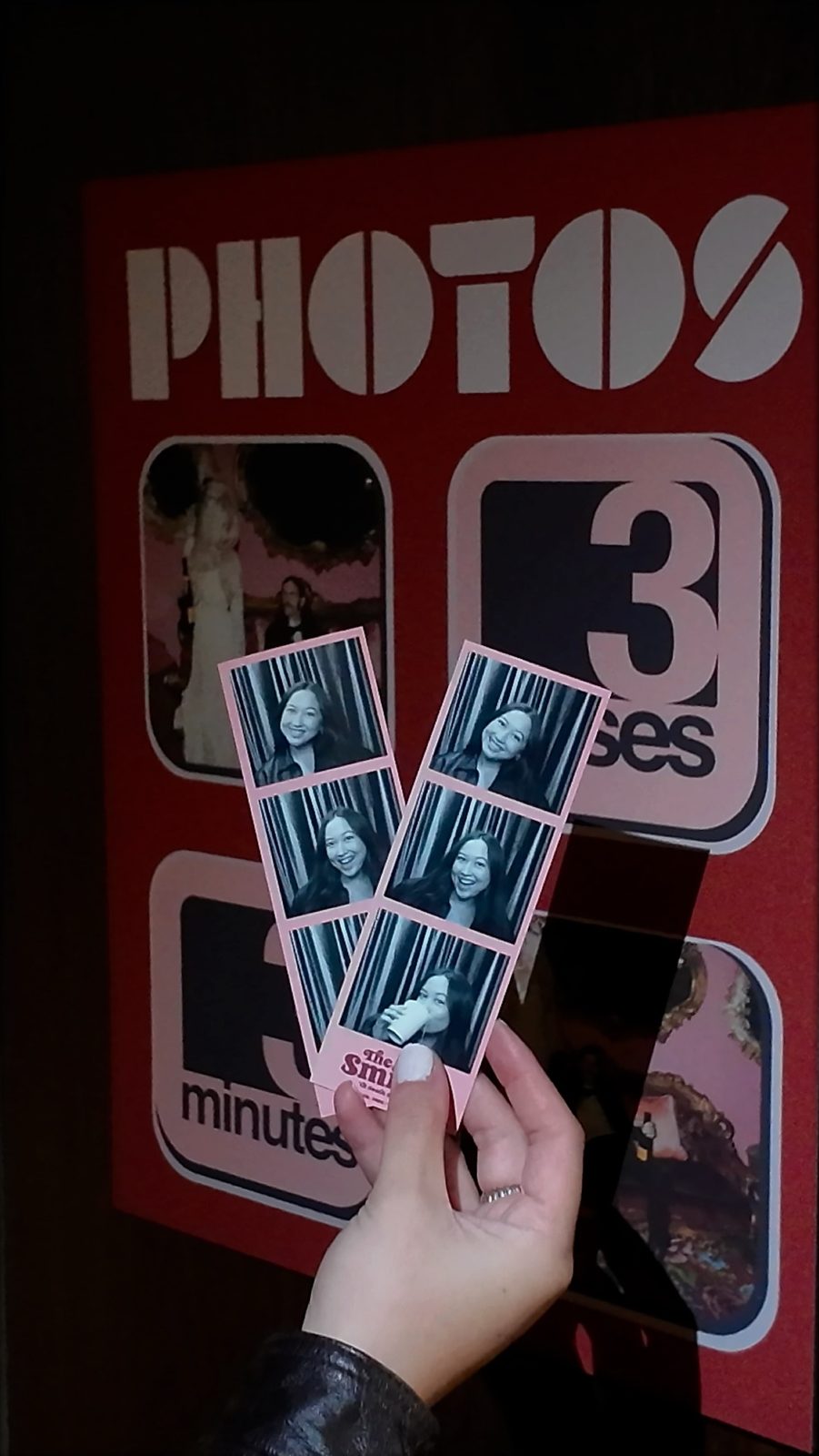 A guest holds two identical black-and-white Vintage Booth photo strips on a pink custom design